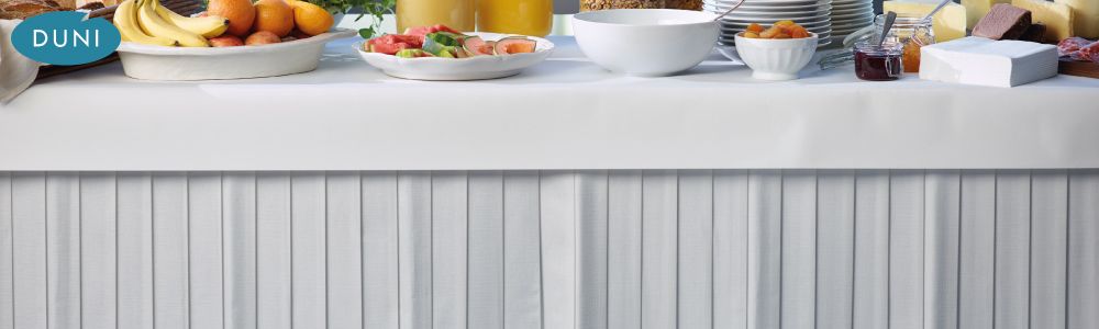 Dunicel® Tableskirt - Dunicel® Tableskirt. Achieve a seamless style in seconds with a table skirt, securely attached thanks to the integrated adhesive tape. Different colours give you the opportunity to match the interiors and to create the perfect atmosphere for any occasion while guaranteeing a spotless and hygienic impression.